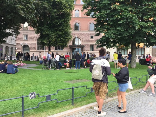 Det är inte bara svenskar som stannar till. Även många turister, kanske på väg från närliggande Gamla stan, stannar till och försöker få en aning om vad vi egentligen alla väntar på.