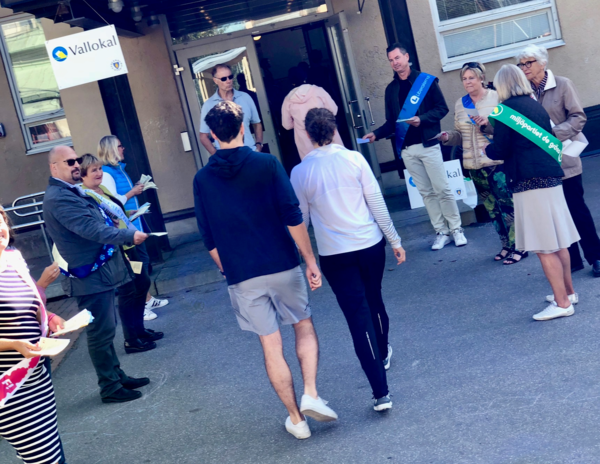 Valarbetare lockar med sina valsedlar när kungsholmsborna anländer till vallokalen i Eiraskolan. Foto: Stefan Bokström, SVT