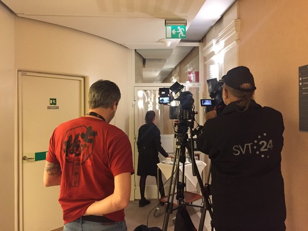Flera fotografer och reportrar är redan på plats i korridoren utanför talman Andreas Norlens kontor. Annie Lööf kommer sannolikt inte att passera förbi precis här, vi får nöja oss med en skymt på avstånd genom en glasdörr när hon går in till talmannen.
