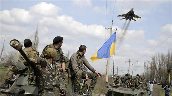 Ukrainska soldater ser på när ett av deras egna stridsflygplan passerar över staden Kramatorsk. Foto: TT.