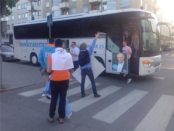 Moderaterna anländer till hejarop i en stor buss och ropar "Hökmark Ole Ole"!