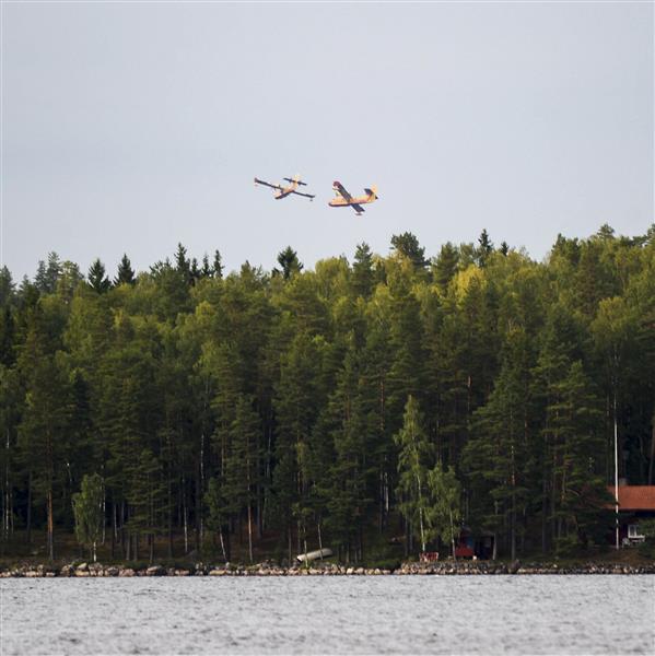 Två av vattenbombningplanen flyger över sjön Åmänningen i skogsbrandsområdet nära Karbenning i Västmanland på onsdagen.
TT
